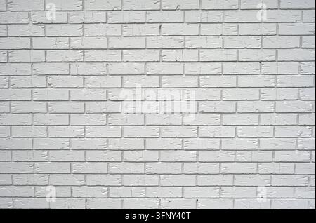 White painted clay bricks with smooth grooved faces, arranged in a standard staggered masonry pattern, with recessed rough mortar joints Stock Photo