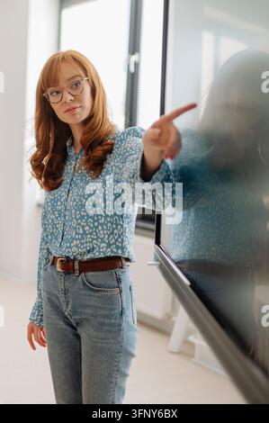Portrait of confident female teacher standing in classroom. Stock Photo