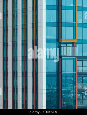 Aerial view of the facade of luxury residential apartments featuring modern glass windows, geometric panels, and vibrant orange accents in Warszawa, W Stock Photo