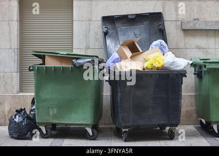 Garbage containers full of waste. City cleaning logistic. Sustainability Stock Photo