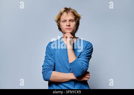 Thoughtful young man touching chin while thinking on studio background Stock Photo