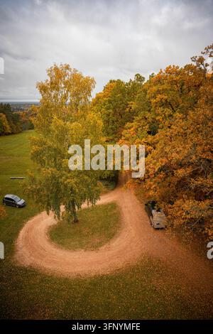 Winding gravel road through colorful autumn trees viewed from above Stock Photo