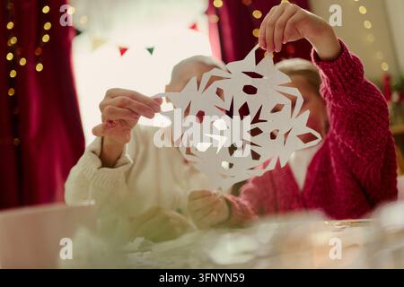 Girl and Senior Woman Holding Paper Snowflake for Winter Holiday Decor Stock Photo