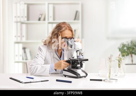 Female scientist looking through a microscope in a laboratory Stock Photo