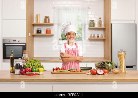 Kid chef behind a counter cutting vegetables in a kitchen Stock Photo