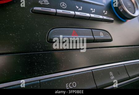 Dusty car dashboard with red hazard warning button, door lock control, climate adjustment switches, airflow icons, and ECO control inside a vehicl Stock Photo