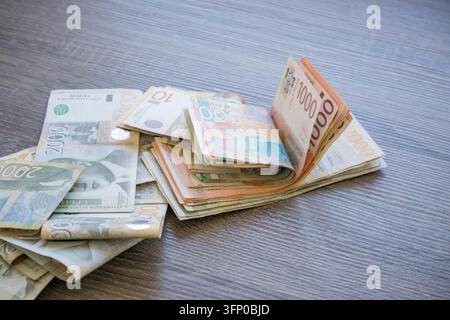 Serbian dinar banknotes in mixed denominations spread across a wooden tabletop, with colorful paper currency, folded stacks, and bundled cas Stock Photo