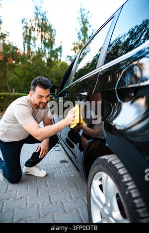 Man polishing black car exterior during auto detailing Stock Photo