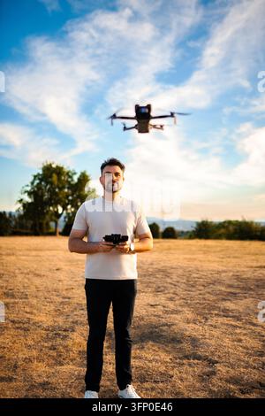 Man operating drone with remote control in field Stock Photo