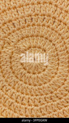 This shows a close up view of a round pattern made from yellow hand crocheted yarn. The texture displays intricate details in the fiber work and desig Stock Photo