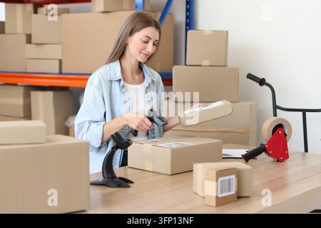 Worker scanning cardboard boxes at table in warehouse Stock Photo