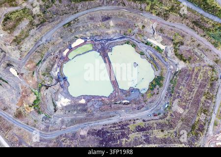 Aerial view of the quarry near Summerhill Drive featuring two light-colored water pools surrounded by terraced earth, dirt roads, and vegetation in Pa Stock Photo