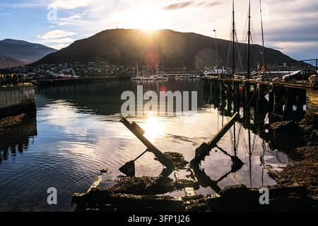 Traditional wooden sailboat and waterfront buildings in Tromsø harbour, Norway Stock Photo