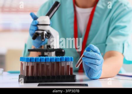 Medical research and blood testing, scientist analyzing samples in laboratory with microscope for clinical diagnosis and healthcare development Stock Photo