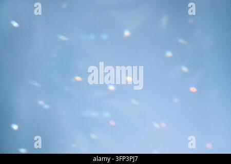 Light refractions creating colorful, shimmering bokeh effects on smooth blue surface Stock Photo