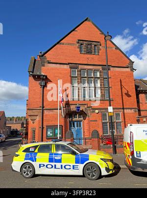 A marked Cheshire Police vehicle is parked in front of a red-brick building, with another police vehicle partly visible. Stock Photo