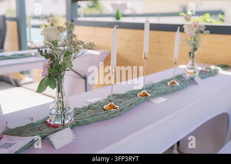 This beautifully decorated wedding table setting features flowers and candles, creating an elegant and romantic atmosphere in a wooden indoor venue Stock Photo