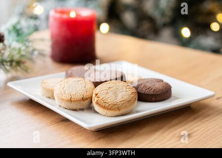 Close-up of assorted Spanish shortbread cookies, including vanilla and chocolate varieties, arranged on a white plate on a wooden table. Traditional s Stock Photo