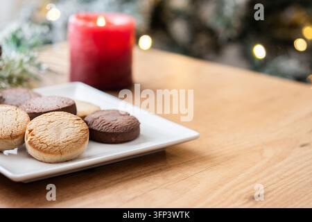 Close-up of assorted Spanish shortbread cookies, including vanilla and chocolate varieties, arranged on a white plate on a wooden table. Traditional s Stock Photo