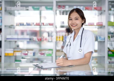 Portrait of asian pharmacist working in pharmacy with medication at pharmacy counter Stock Photo