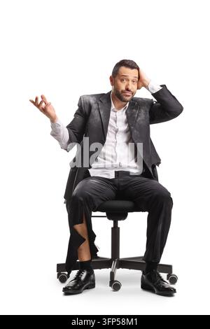 Confused businessman sitting in an office chair with a torn suit covered in dust isolated on white background Stock Photo