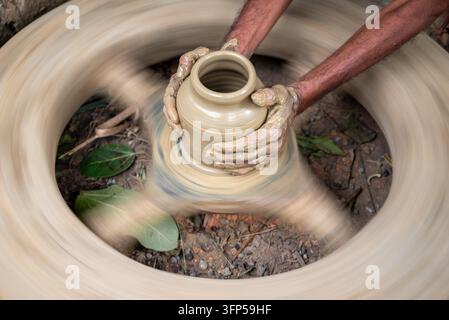 Joypurhat, Rajshahi Division, Bangladesh - 23 September 2026: View of a potter shaping a clay pot on a spinning wheel with hands covered in wet clay. Stock Photo