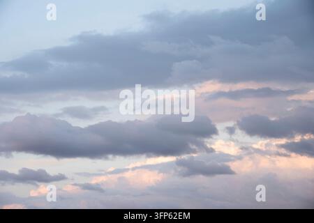 Beautiful sky background. Light blue sky with soft pink, orange and grey clouds. Perfect for cloud exchange. Stock Photo