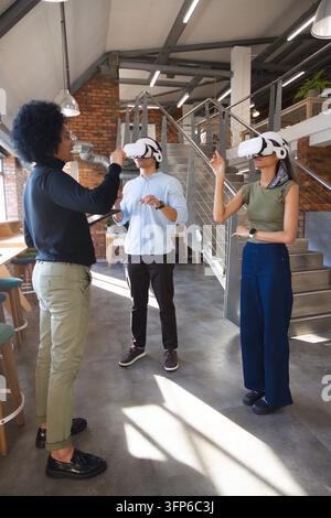 Diverse coworkers demonstrating VR training in loft office with white headsets and tablet Stock Photo