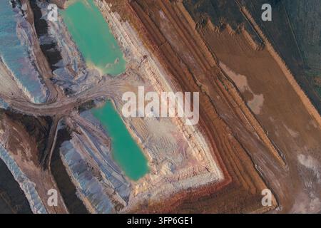 Aerial drone view of the vibrant abstract pattern of an active pit. Geometric pools of light, teal chemical water contrast sharply with white rock and Stock Photo