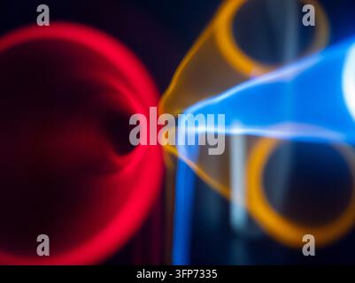 An abstract visual art composition featuring glowing neon light streaks in vibrant red, blue, and yellow colors, creating dynamic flowing shapes and f Stock Photo
