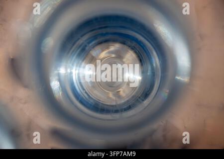 An abstract macro view looking straight down into a clear plastic water bottle creating a swirling light vortex. Stock Photo