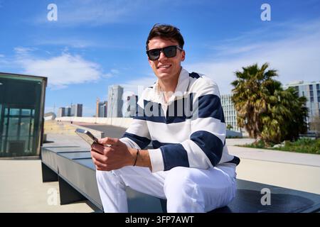 Young man smiling using smartphone in urban setting Stock Photo