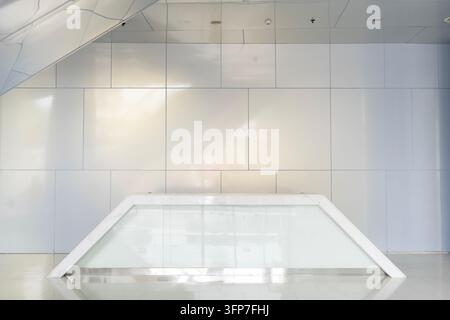 Modern minimalist reception area with sleek white panels and glass counter. Empty space evokes calm professionalism and clean corporate design. Ideal Stock Photo