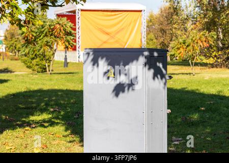 Industrial power distribution cabinet casting leaf shadows on green grass Stock Photo
