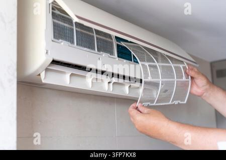 A male air conditioner technician or air conditioner installation. Technician is repairing the air conditioner in houses and buildings Stock Photo