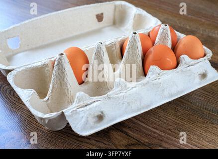 Brown chicken eggs placed in an open eco-friendly paper carton package resting on a wood background. Sustainable food packaging, farm produce delivery Stock Photo