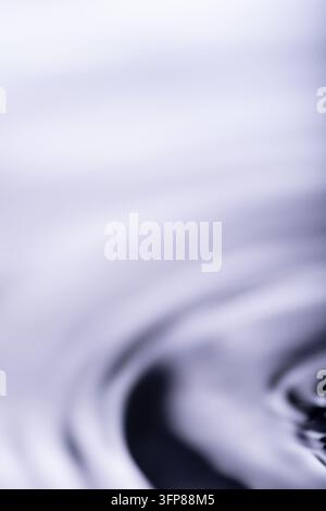 268.Close-up of water surface showing concentric ripples from droplet impact. Smooth gradient of blue and gray tones creates a soft, abstract visual w Stock Photo