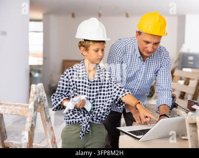 Portrait of man architect and boy using laptop while discussing working process in house being renovated Stock Photo