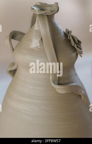 Unfired clay vase with intricate decorative elements and sculpted handles, showcasing the raw beauty of handmade ceramics and the creative process in Stock Photo