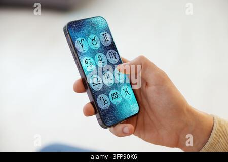 Man using astrology app on his smartphone indoors, closeup Stock Photo