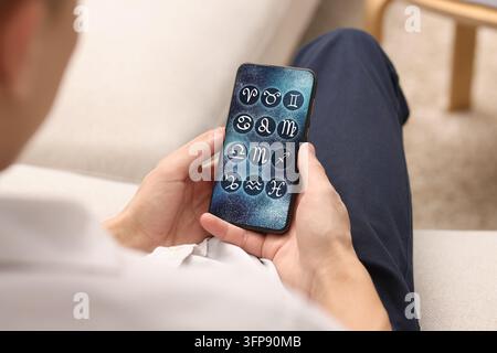 Man using astrology app on his smartphone indoors, closeup Stock Photo