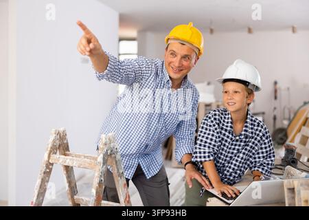 Portrait of man architect and boy using laptop while discussing working process in house being renovated Stock Photo