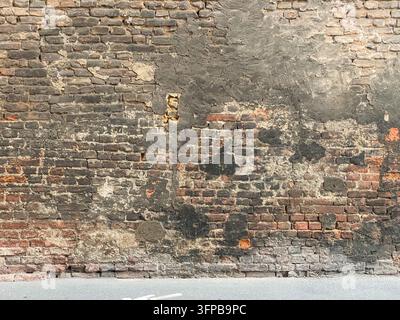 Old brick wall exhibiting weathered textures and decaying stucco, forming a rustic background for architectural design elements and a conceptual repre Stock Photo
