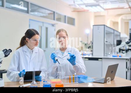 Female scientists collaborating in a modern laboratory, conducting experiments and research, wearing safety glasses and lab coats while working with s Stock Photo