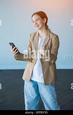 Smiling young woman celebrating online success on smartphone Stock Photo