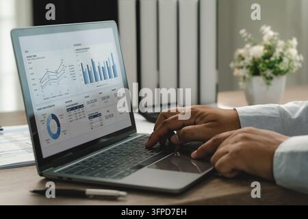 Businessman using laptop with financial dashboard and charts for data analysis, performance review and business reporting in office. Stock Photo