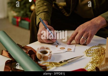 Man Writing Christmas Gift Tags for Holiday Presents Stock Photo