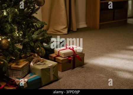 Wrapped Gift Boxes Placed under Decorated Christmas Tree at Home Stock Photo