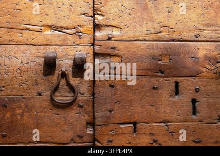 Close-up of weathered wooden door with old wrought iron ring and visible old nails, Gubbio, Umbria, Italy Stock Photo