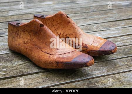 Traditional wooden shoe lasts used in shoemaking, showing worn surfaces and craftsmanship, photographed on weathered wooden boards. Stock Photo